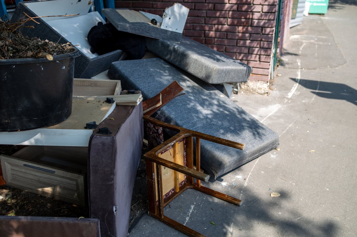 Pile of discarded household junk, old mattress, chair and broken drawers left outdoors