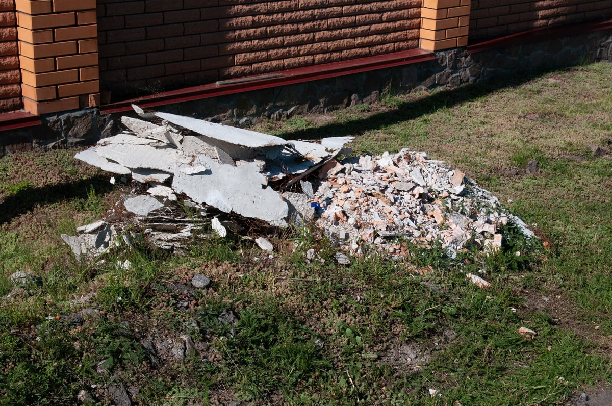 Pile of discarded construction debris, broken concrete and brick rubble on grass