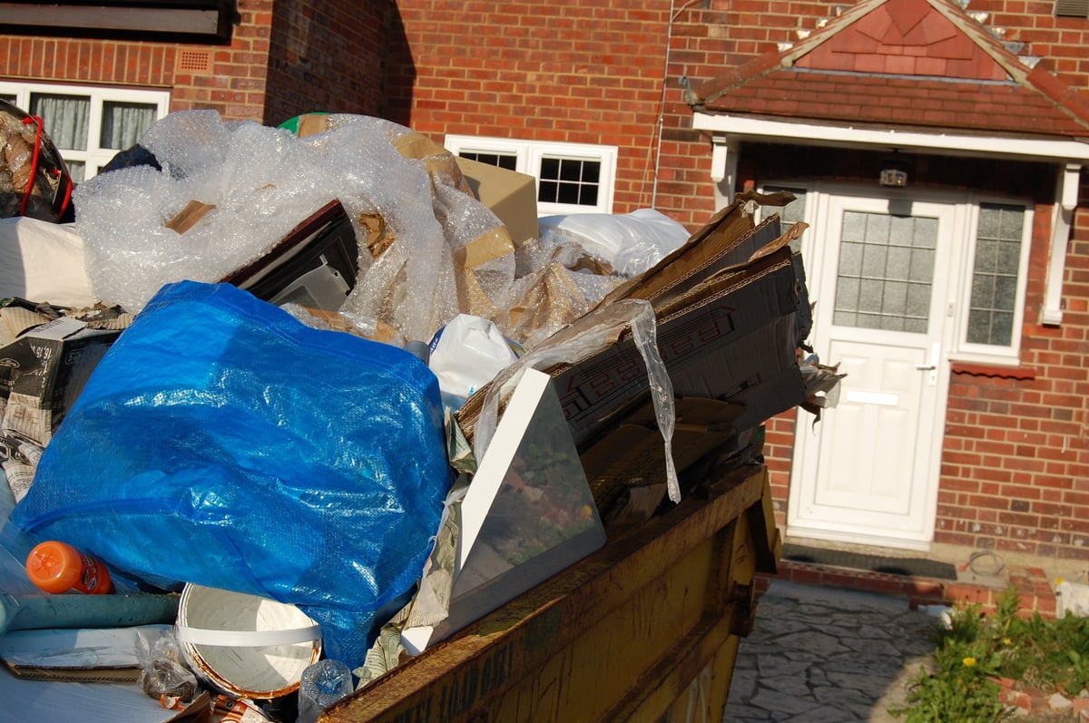 Overflowing dumpster full of trash and debris in front of a house